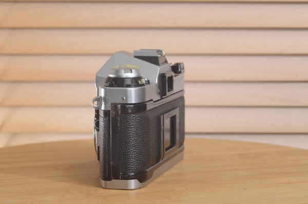 Canon AE1 P 35mm SLR camera body by Rewind Cameras, shown with textured grip and control dials on front and top.