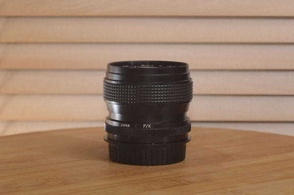 Vivitar Zoom PK Pentax 28-50mm f/3.5-4.5 camera lens with focus and zoom rings, mounted on a camera body.